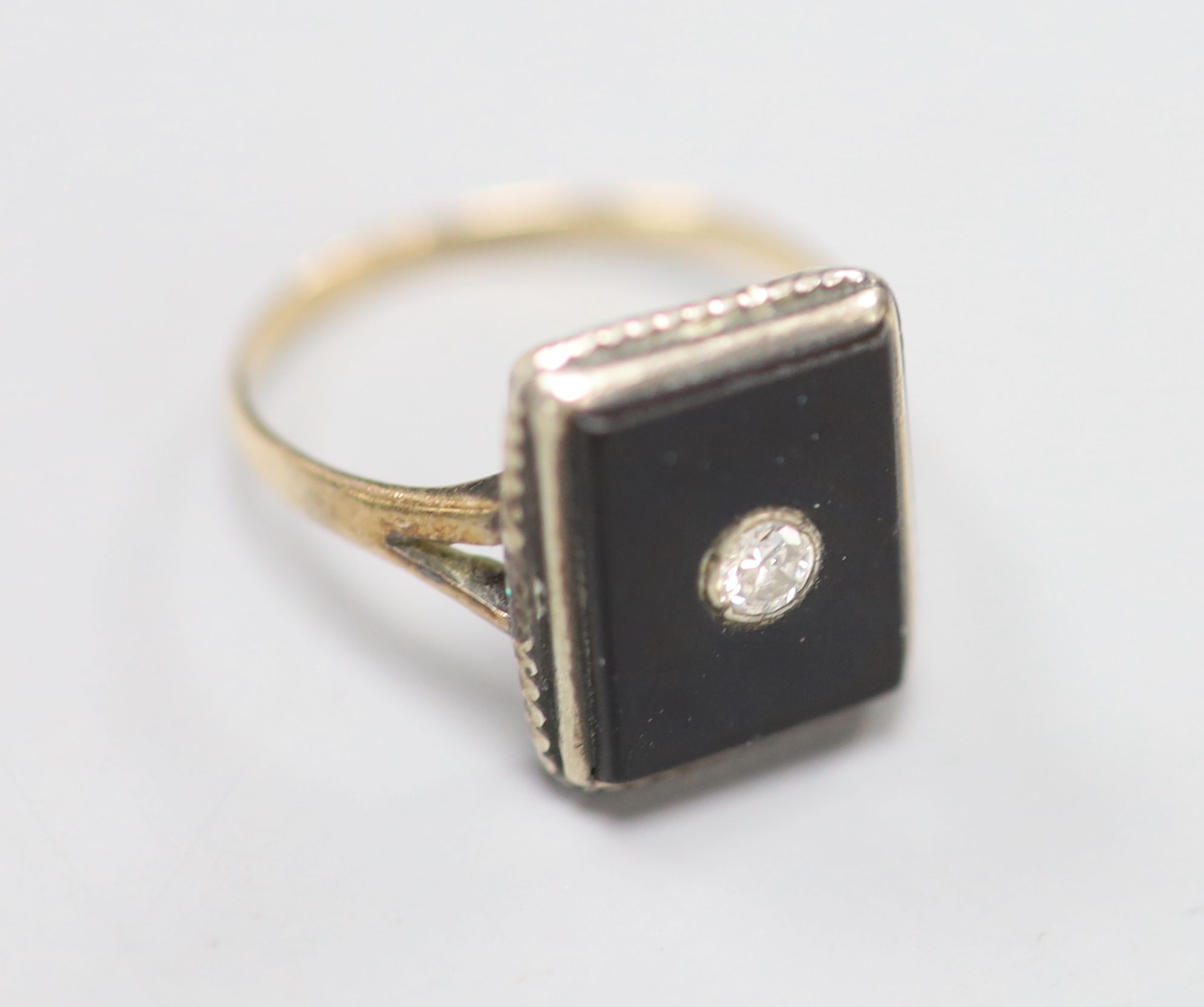 A yellow metal, black onyx and diamond set rectangular ring, size M, gross 2.4 grams.